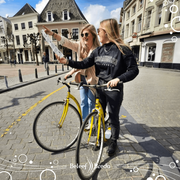 Twee meiden die met de step in Breda zijn. Ze staan op gele steps en zijn op een kaart aan het kijken waar zij heen moeten.